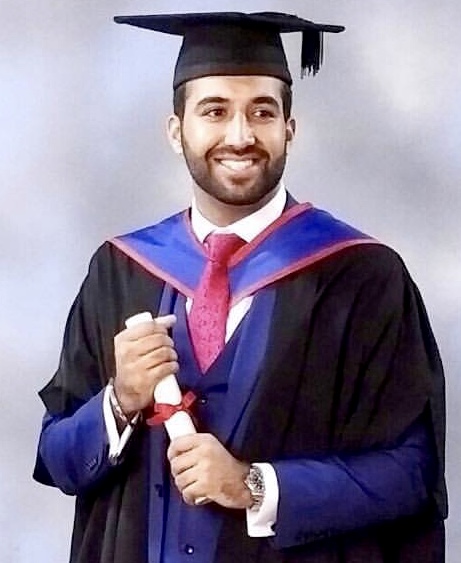 Juj at graduation holding a degree scroll